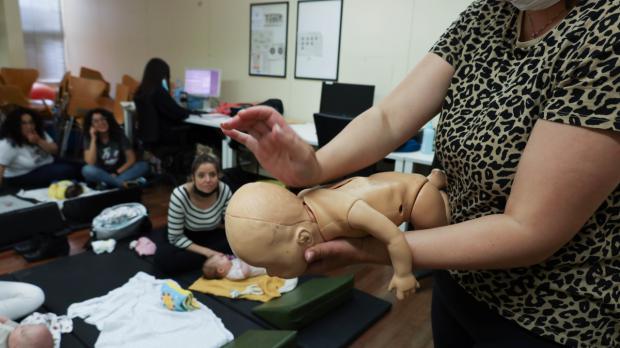 Una mujer del grupo de posparto del ASSIR Ramona Via practica la técnica de primeros auxilios de golpes secos entre los hombros con un maniquí de reanimación