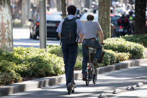 Un patinete eléctrico y una bicicleta circulando por un carril bici.