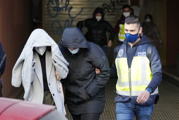 Un agente de la Policía Nacional acompaña a dos de los detenidos en la operación de este lunes en el Ayuntamiento de Cornellà.Enric Fontcuberta (EFE)