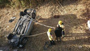 Actuación de los bomberos ante el coche volcado en la riera.