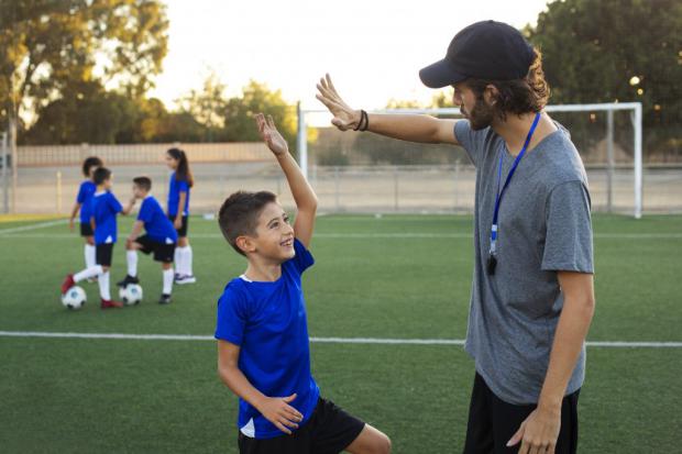 Entrenador felicitando a un joven futbolista