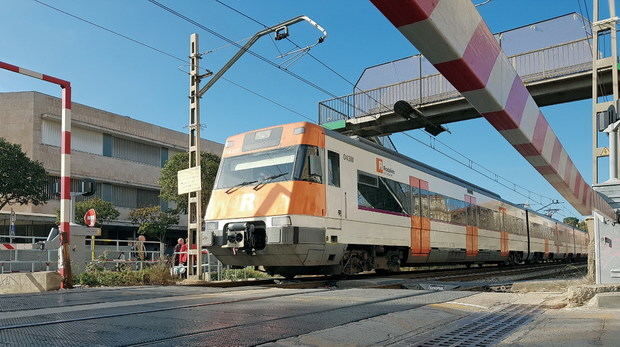 Tren de Rodalies circulando por el paso a nivel de Sant Feliu