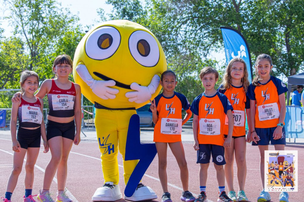 Imatge dels nens i nenes de l'escola amb la mascota de L'Hospitalet Atletisme.