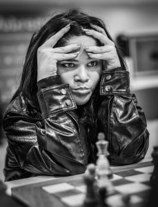 Jugadora de ajedrez concentrada con manos en la cabeza